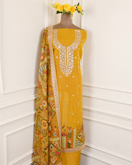 Yellow embroidered dress with a patterned dupatta on a mannequin against a white wall.