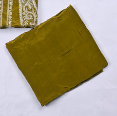 Folded green fabric with embroidered pattern on a white background