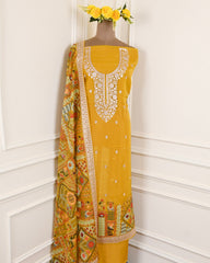 Yellow embroidered dress with a patterned dupatta on a mannequin against a white wall.
