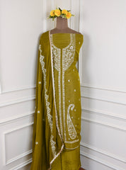 Green embroidered dress on a mannequin against a white wall with yellow flowers.
