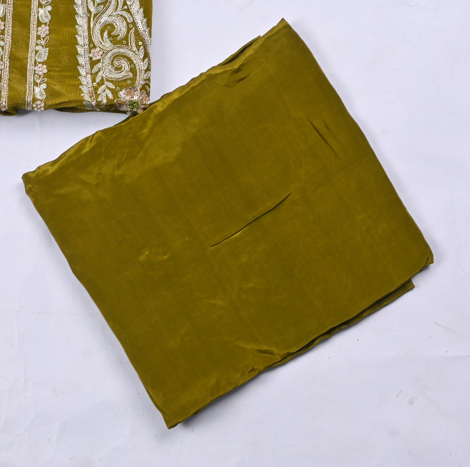 Folded green fabric with embroidered pattern on a white background