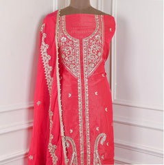 Red embroidered garment on a mannequin against a white wall