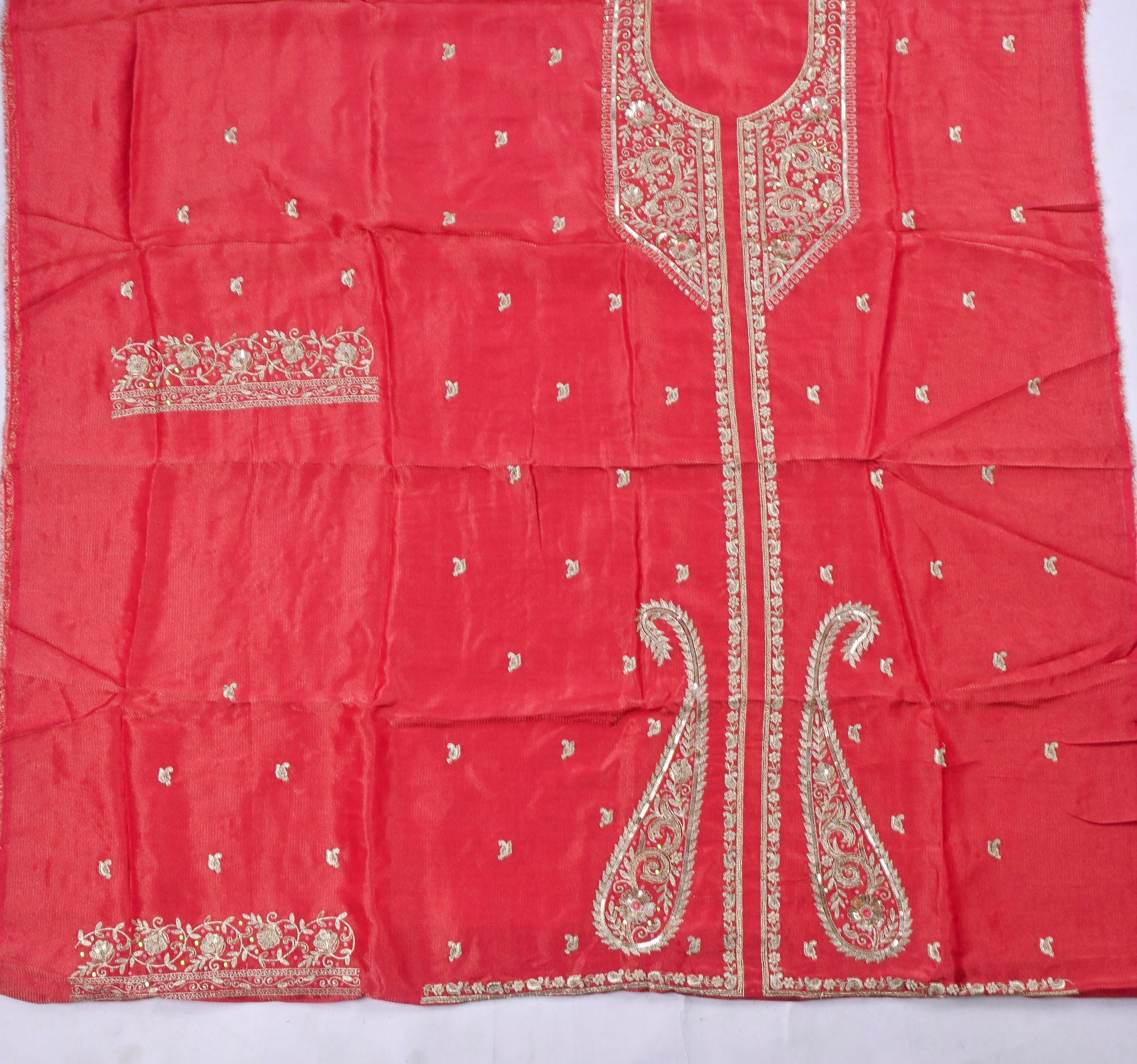 Red fabric with intricate white embroidery on a white background