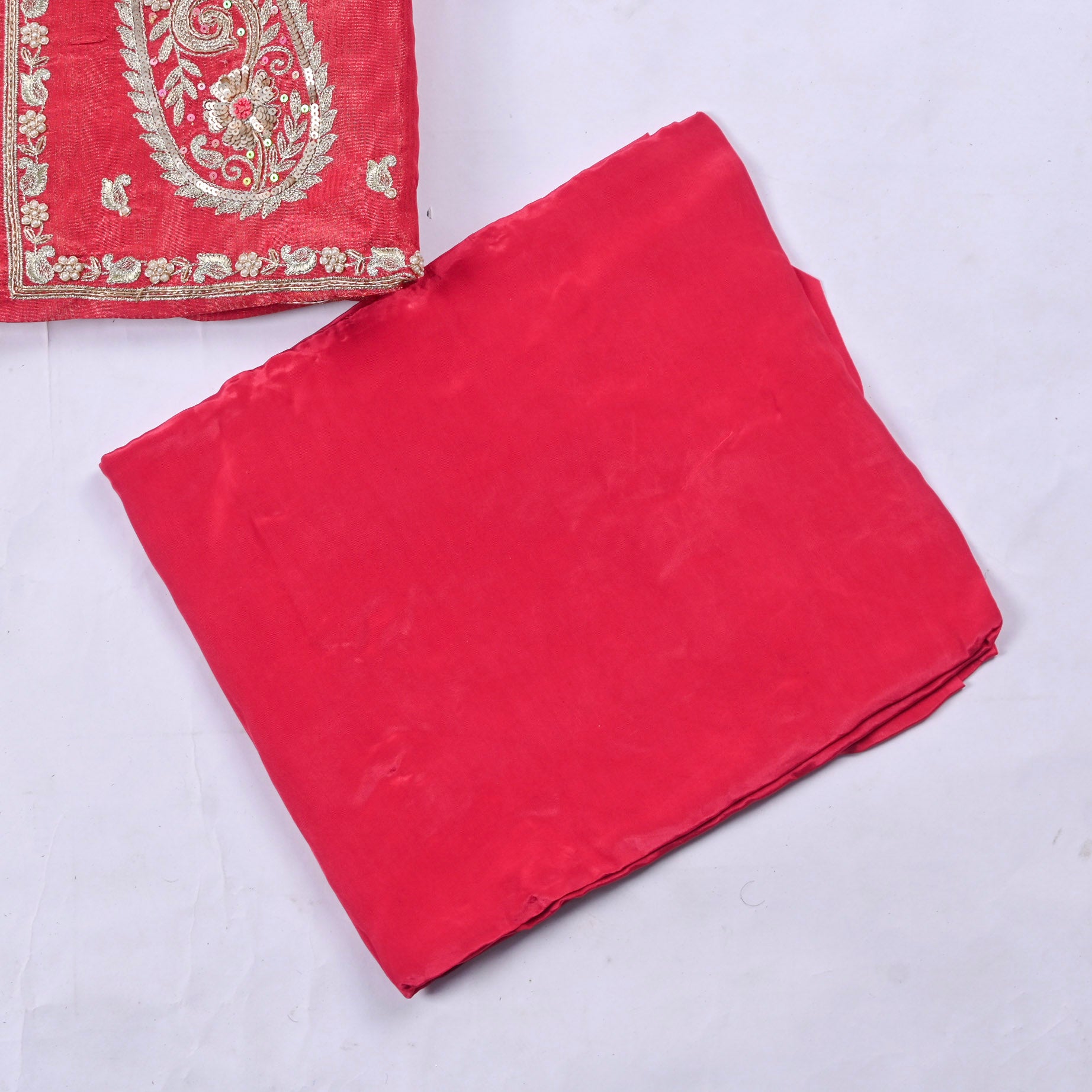 Red fabric with gold embroidery on a white background