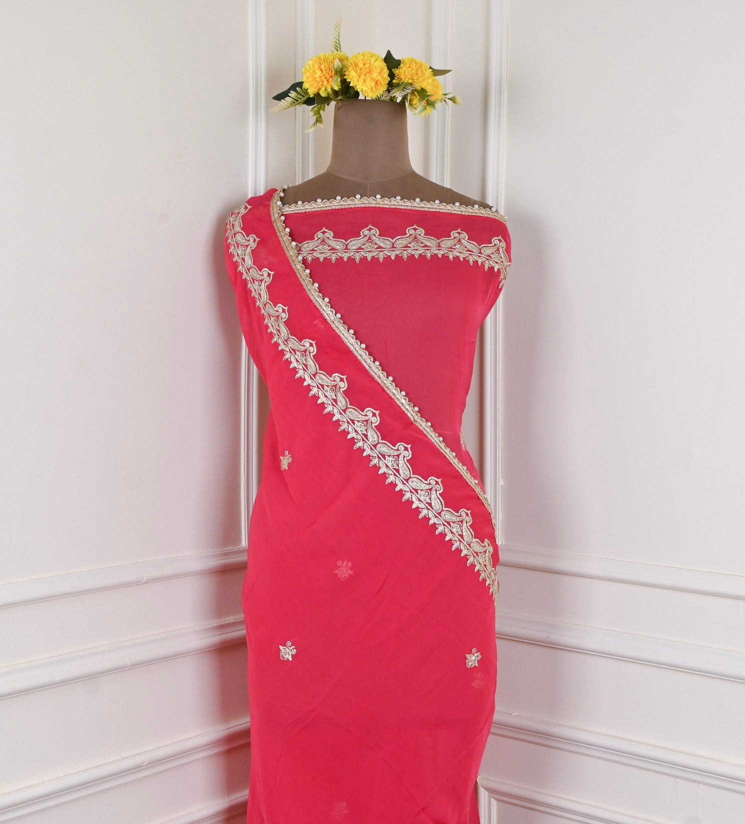 Red saree with white embroidery on a mannequin against a light background