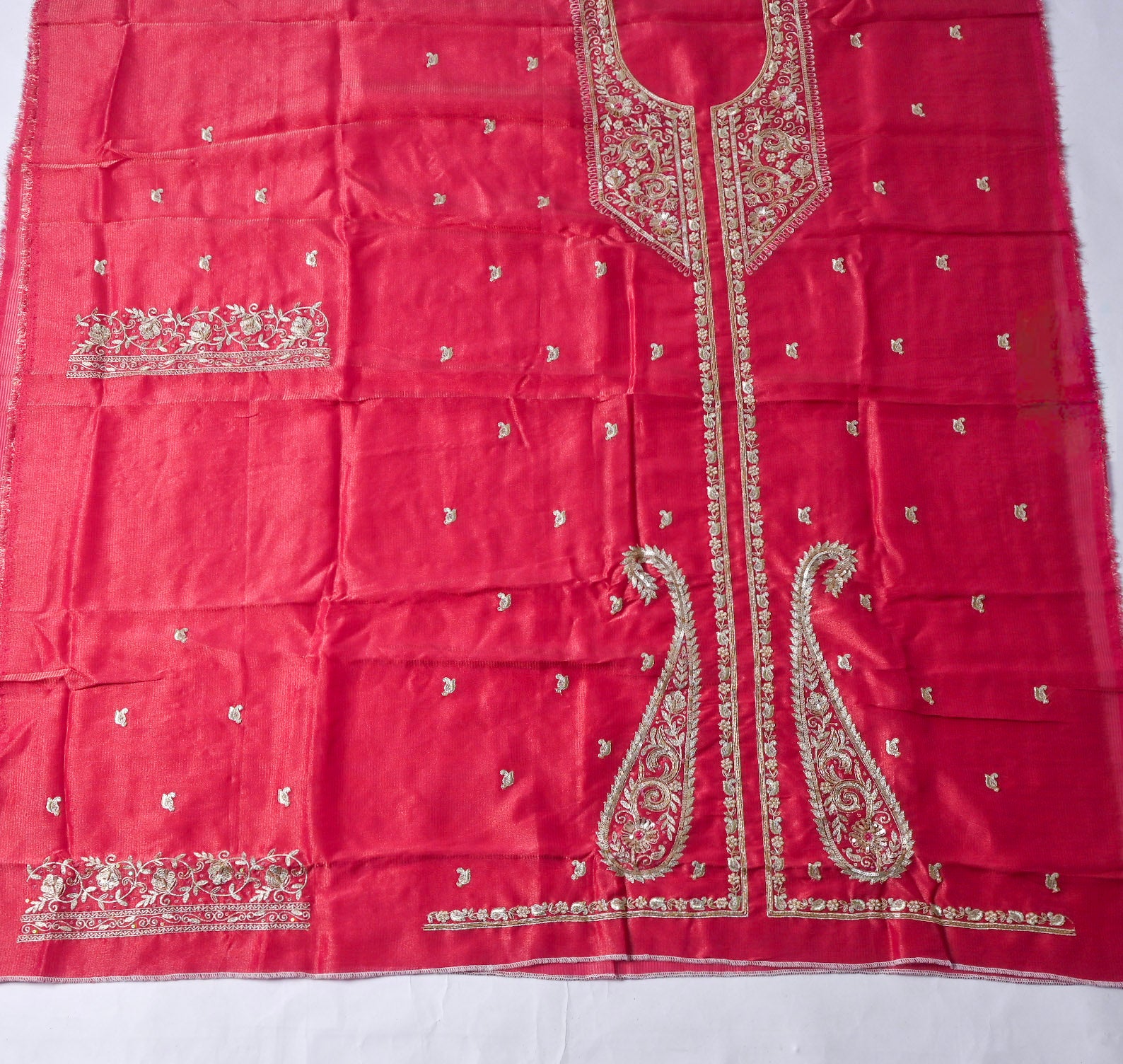 Pink fabric with intricate gold embroidery on a white background