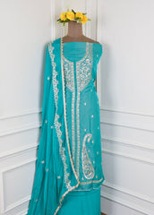 Turquoise saree with white embroidery on a mannequin against a white background