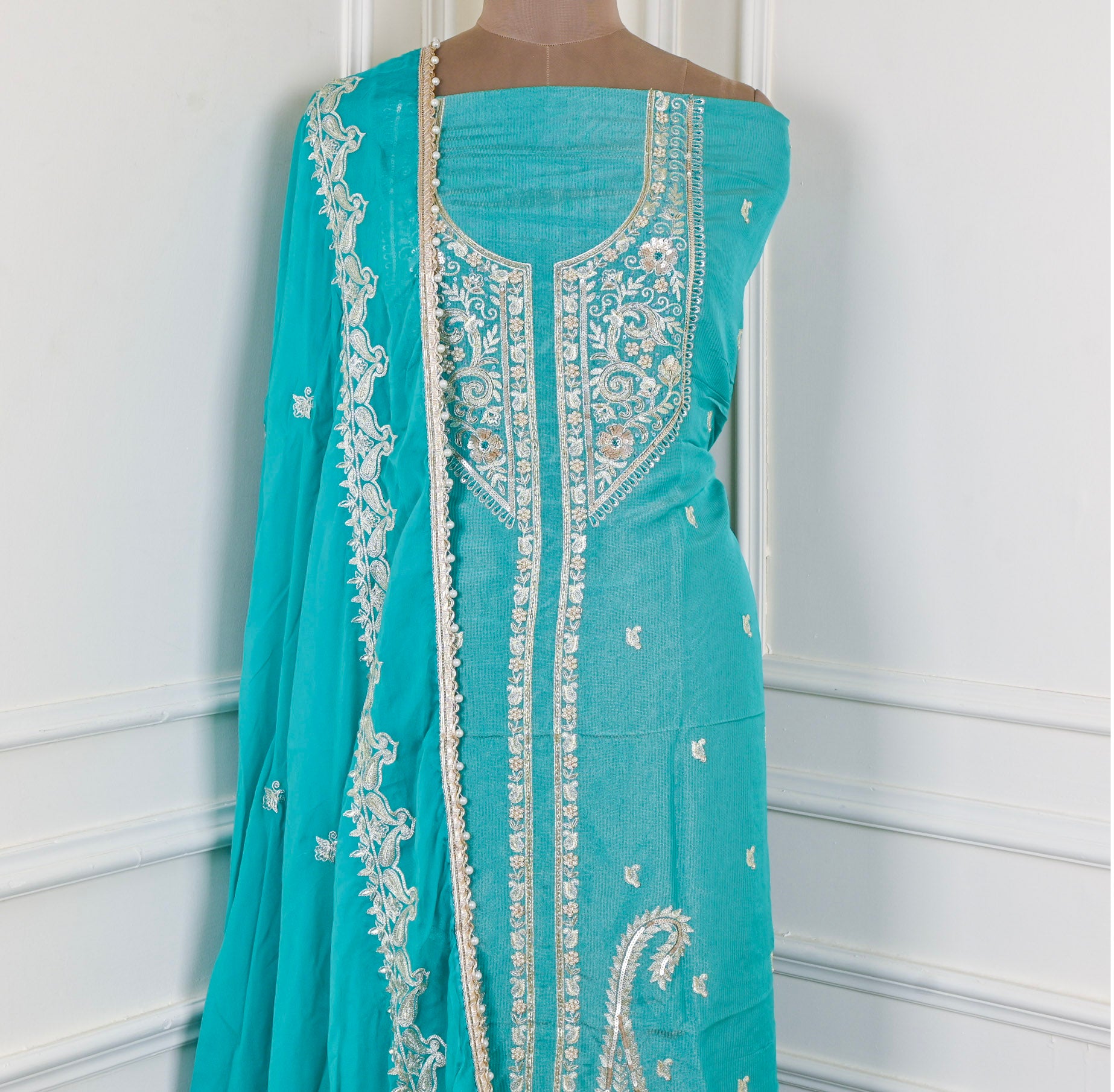 Turquoise saree with intricate white embroidery on a mannequin against a white background