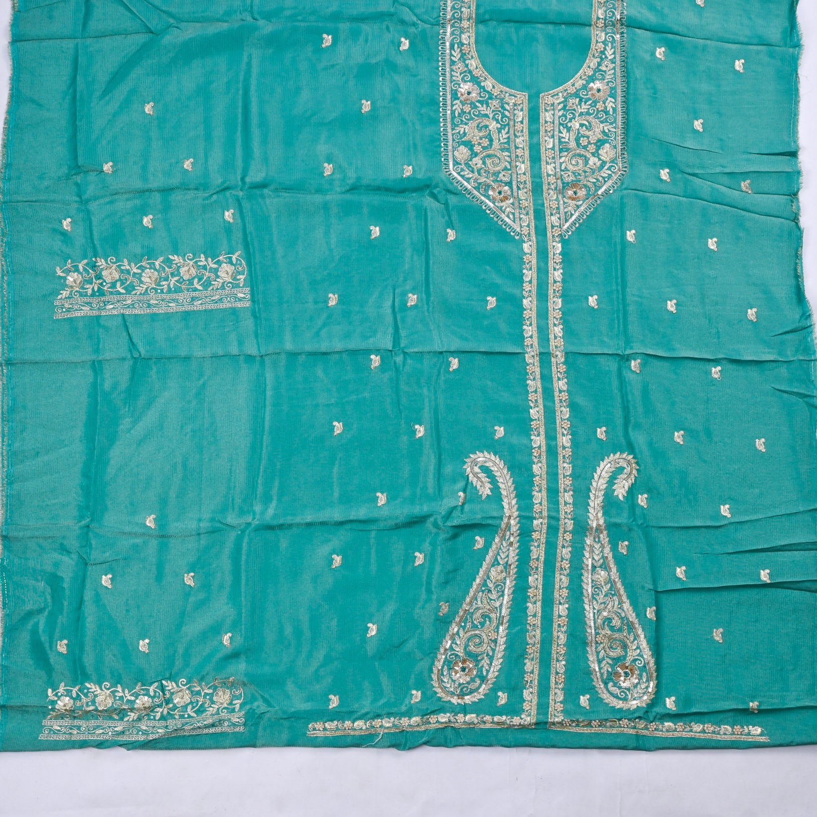 Teal fabric with intricate white embroidery on a white background