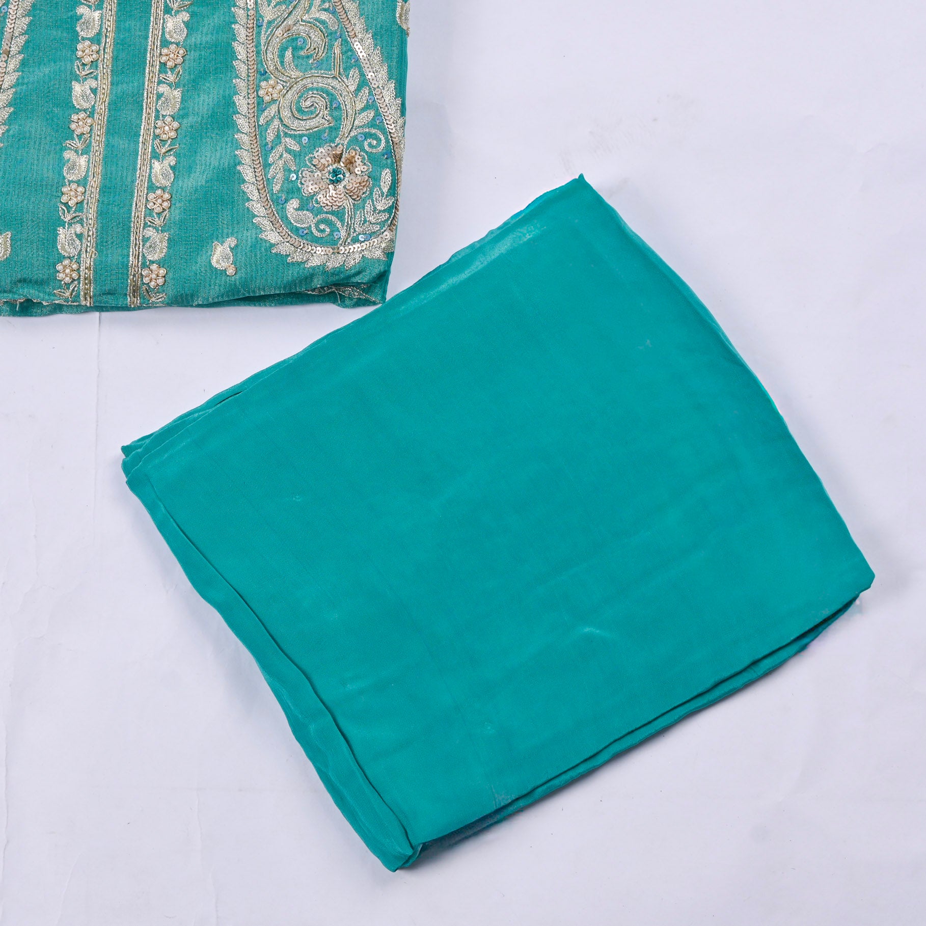 Teal fabric with embroidered pattern on a white background